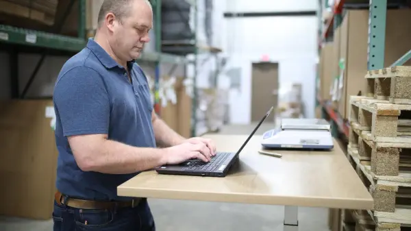 An engineer types on a laptop in an industrial facility, working to optimize con