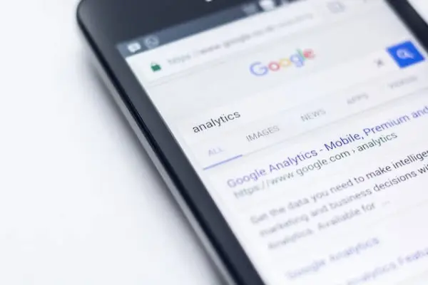 A google search with optimized meta descriptions appear on a cell phone