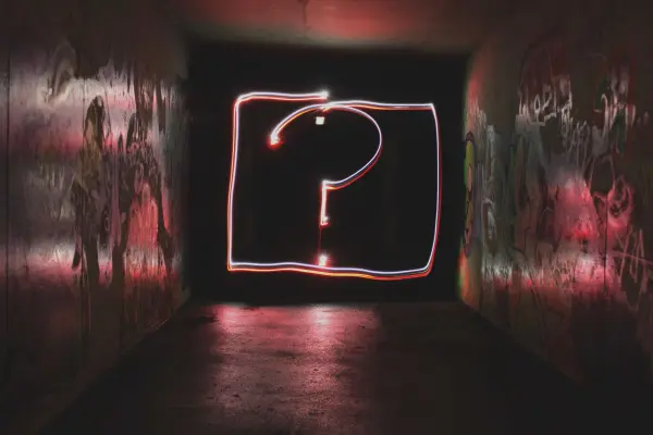 A glowing red question mark in a dark room