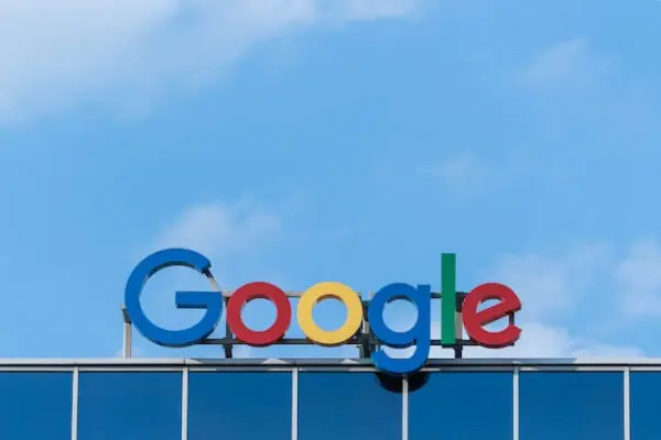The Google sign mounted on top of a building and in front of a clear blue sky
