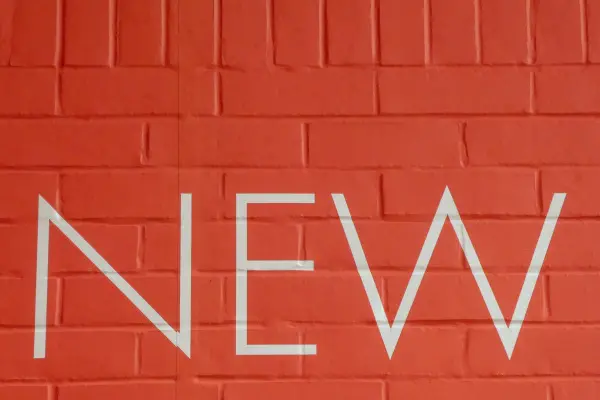 A orange brick wall with the word NEW in all white letters
