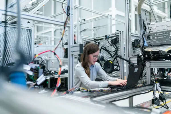 A worker sits in a factory and types on a laptop as they learn the difference be