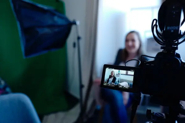 A woman sits in front of a camera as she records an industrial B2B vlog