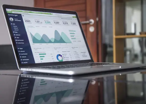 An open laptop displays graphs and charts showing upward trends from successful