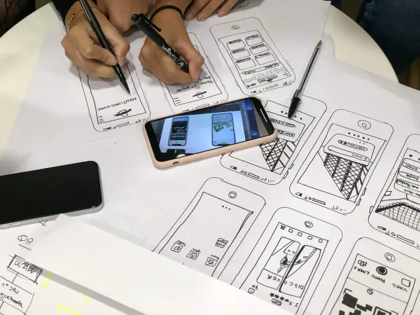 A smartphone sits on top of a plan for mobile website layout