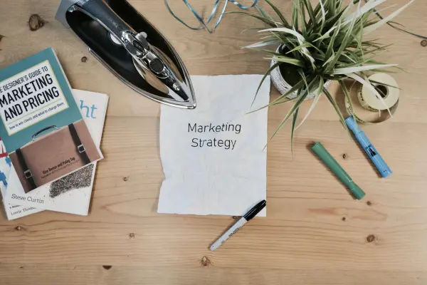 A crumpled paper with the words Marketing Strategy sits on a cluttered desk surf